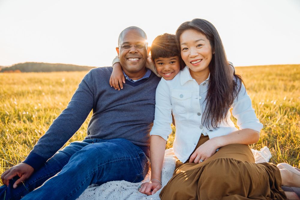 Family sitting together in golden wheat field during sunset.