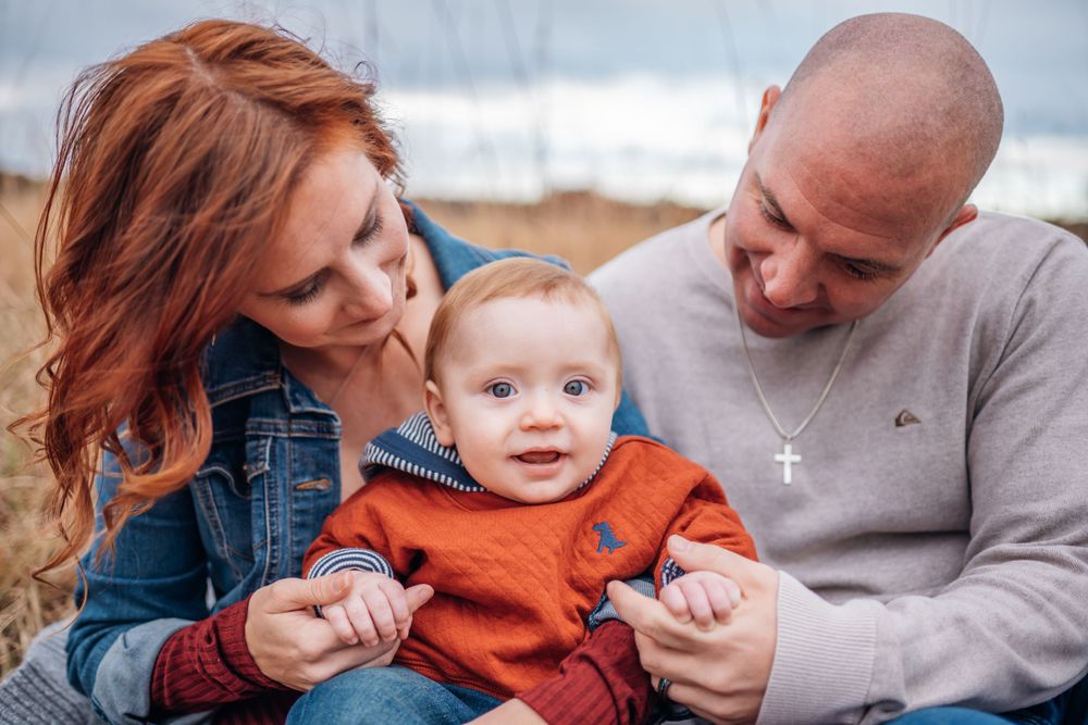 A family shares an intimate moment together outdoors on a cloudy day.