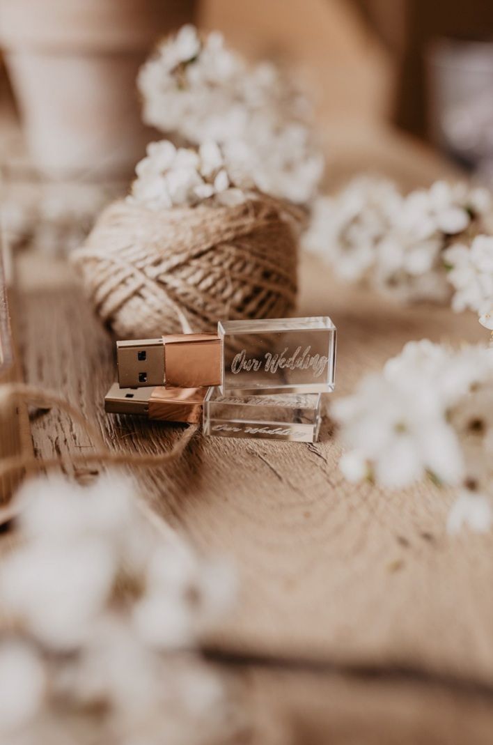 A rustic styled photo of twine and white flowers with a crystal USB drive on wooden surface.