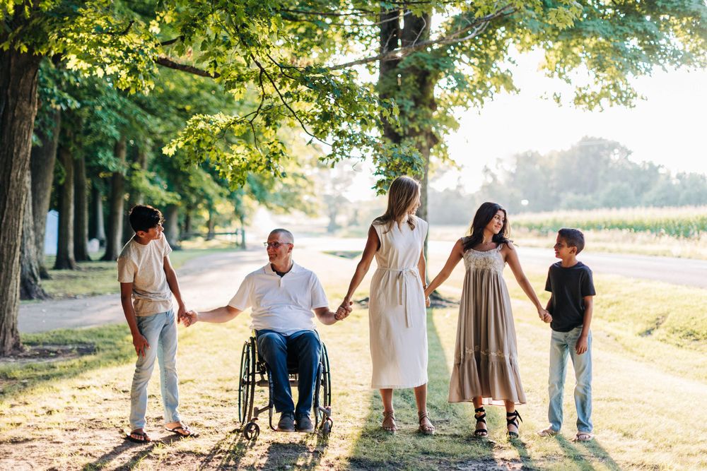 Diverse group walks together on tree-lined path with wheelchair user.