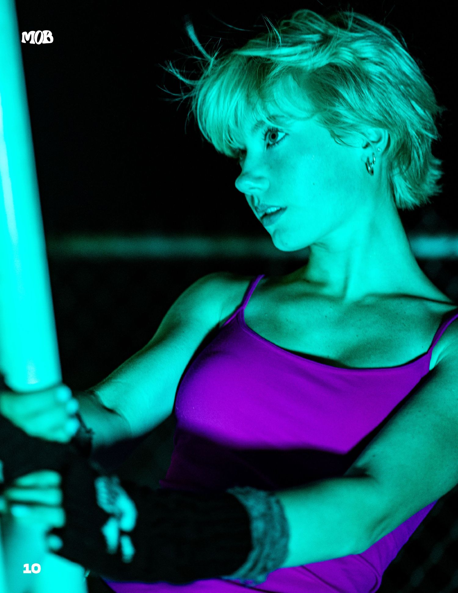 Dramatic portrait with purple top illuminated by teal lighting.