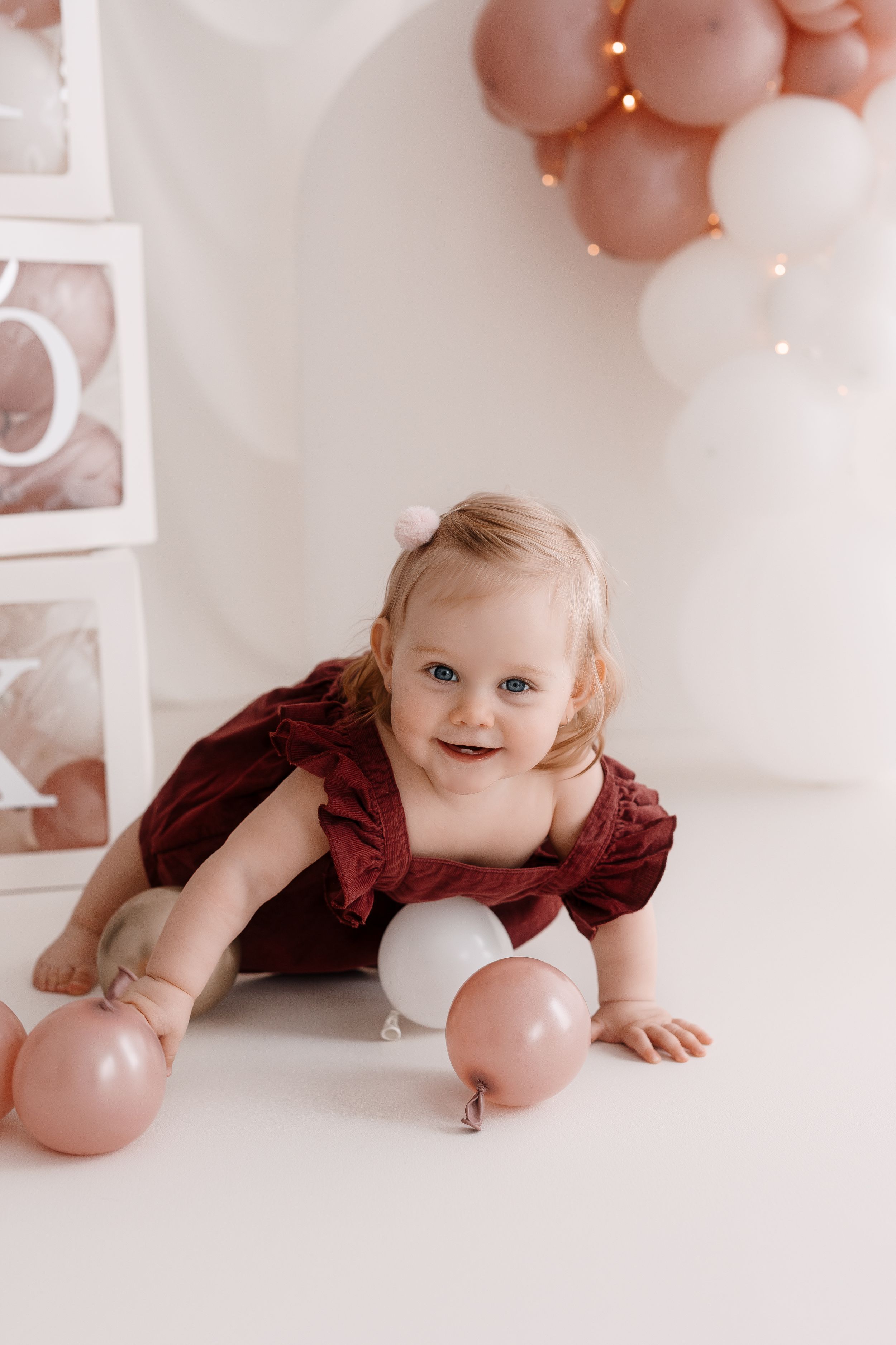 Festive photo setup with pink and white balloons and decorative blocks in studio setting.