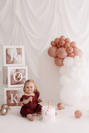A festive first birthday setup with decorative blocks spelling ROK, balloons, and a small cake.