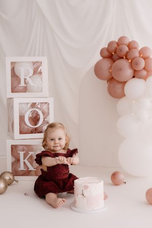 Birthday photoshoot setup with decorative blocks, rose gold balloons, and a small cake.