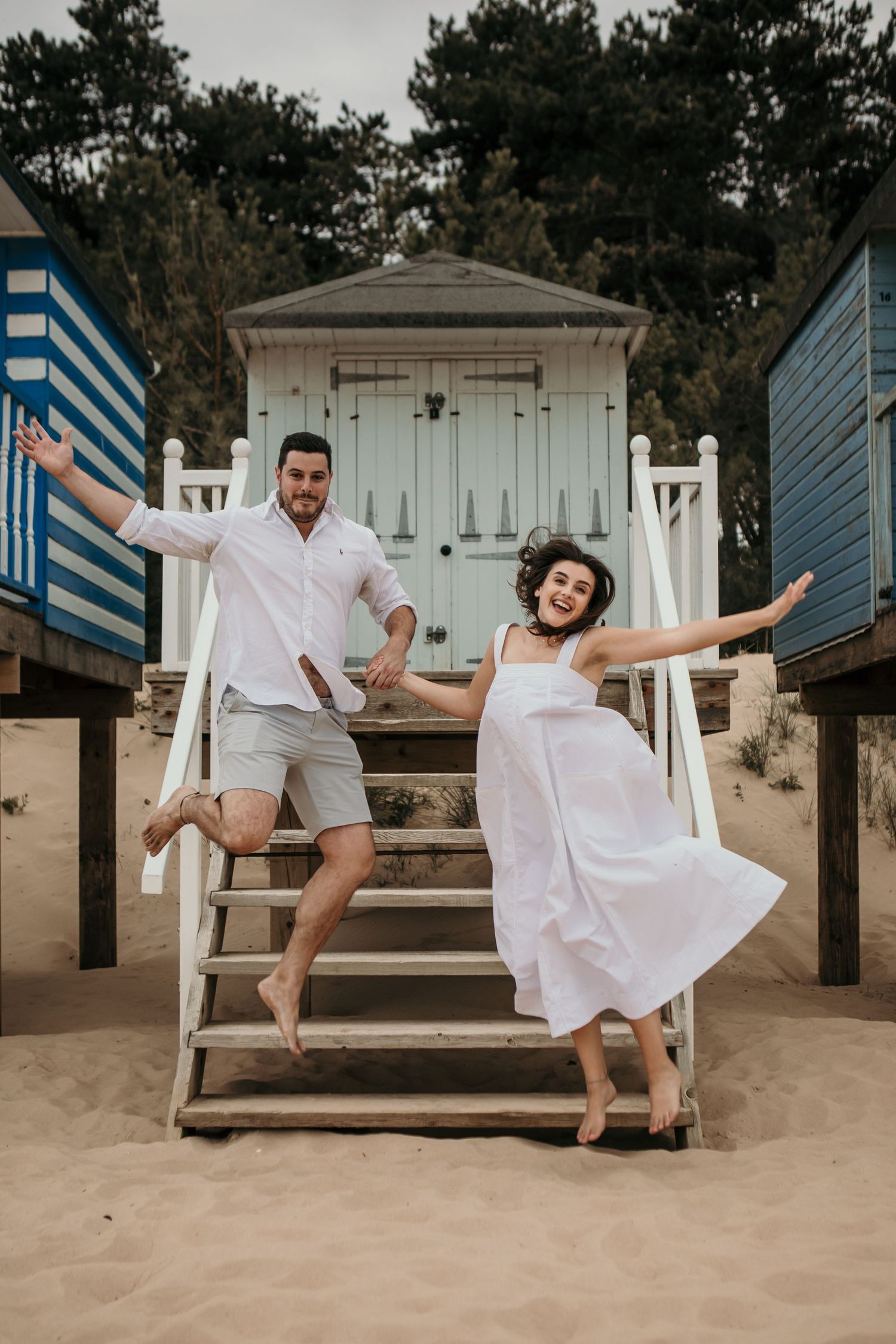 couple jumping of beach huts