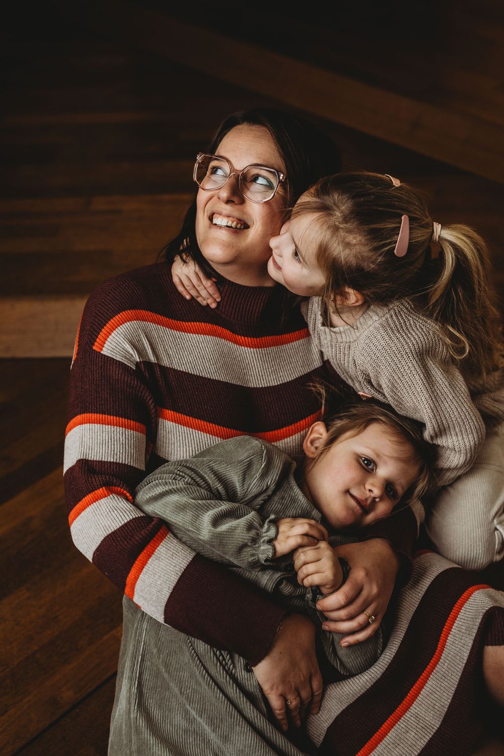 Family portrait in cozy winter sweaters against wooden wall background.