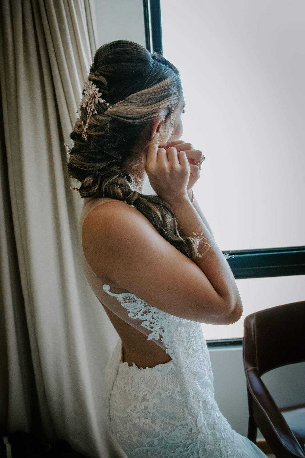 Elegant bridal styling with lace wedding dress and delicate hair accessories near a window with natural light.