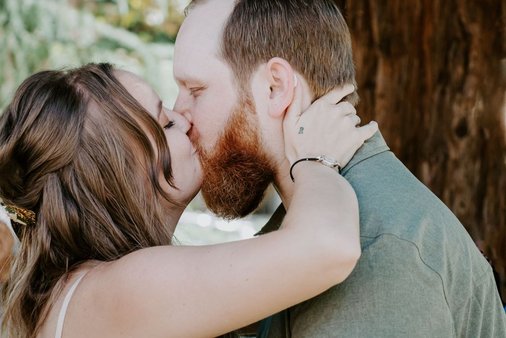 Intimate moment between two people sharing a romantic kiss against a rustic wooden backdrop.