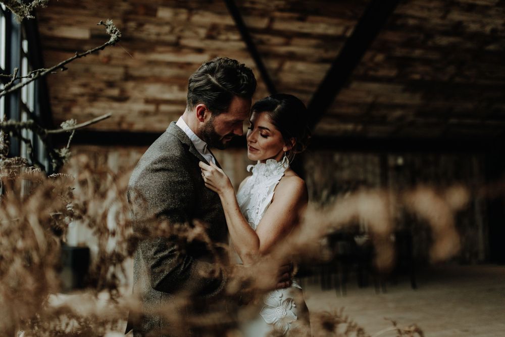 An intimate wedding moment captured in a rustic barn setting with warm lighting.