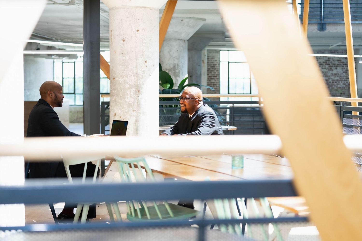 Modern office interior through glass windows showing a business meeting in progress.