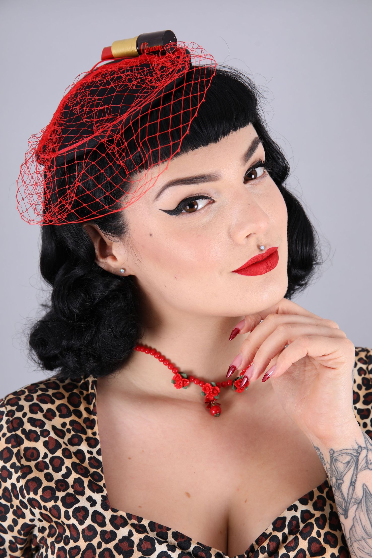 Vintage pinup styled model with red accessories smiling to camera in a photography studio in Shoreham.