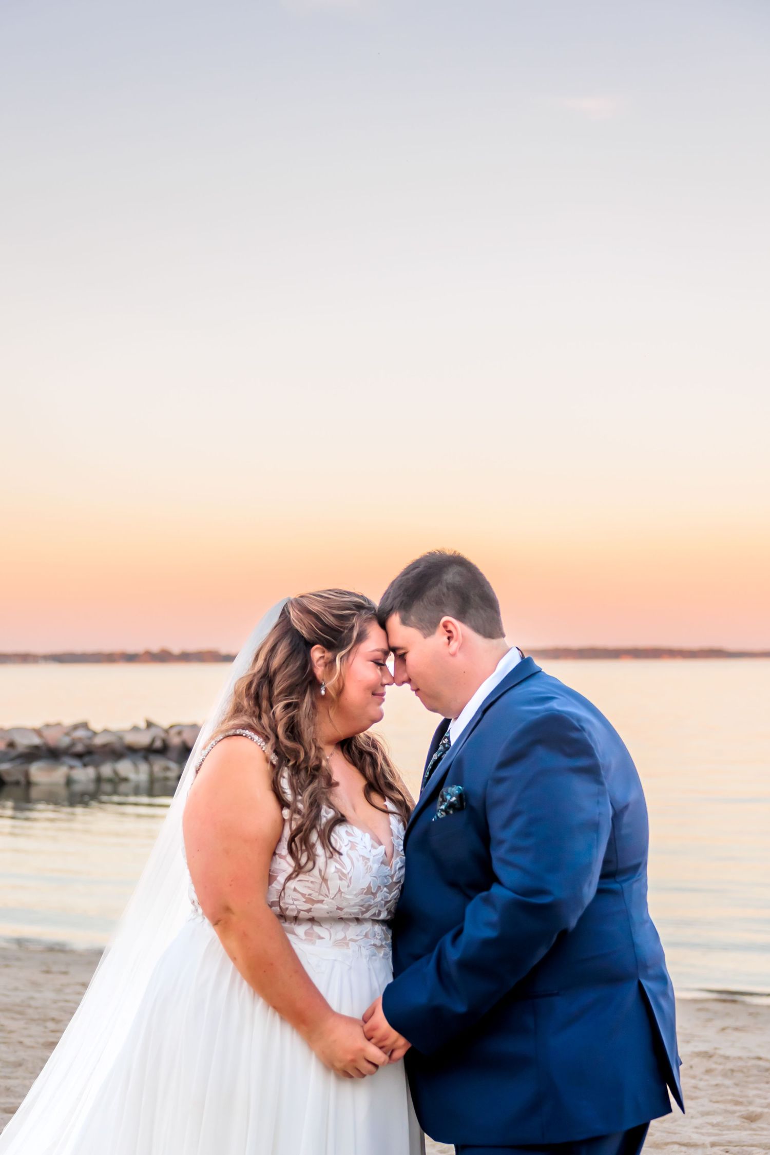 A romantic sunset beach wedding portrait showing a tender moment between newlyweds.