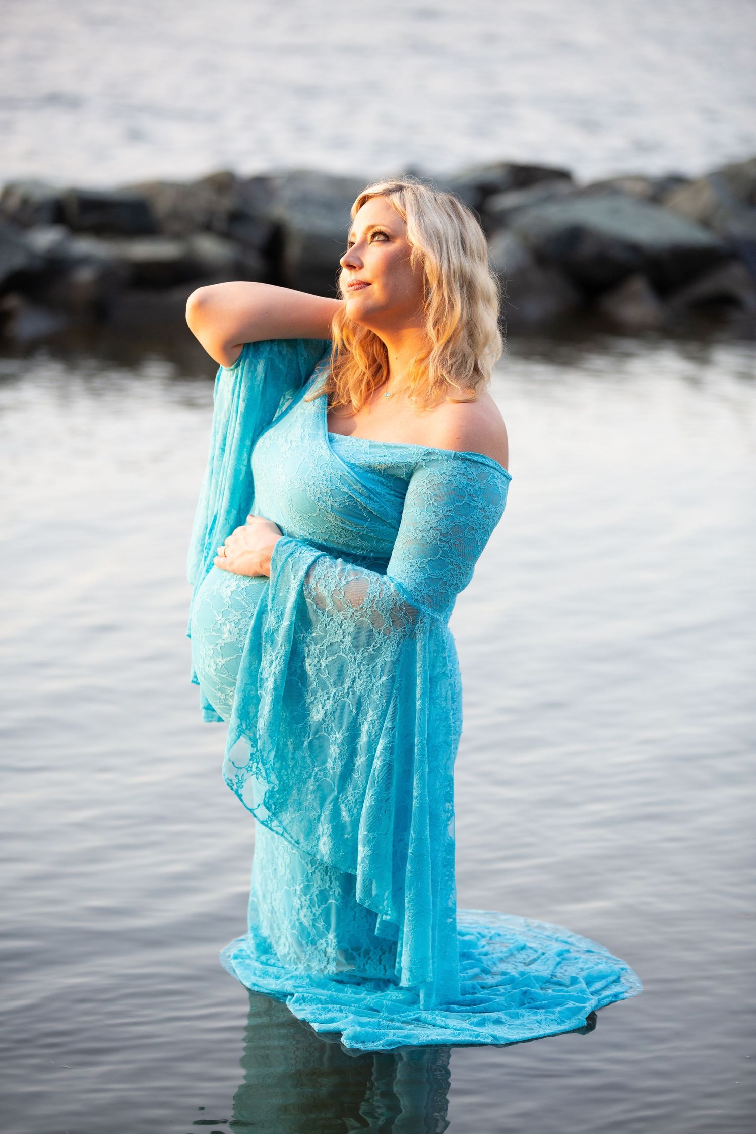 a woman is standing in water and wearing a blue gown