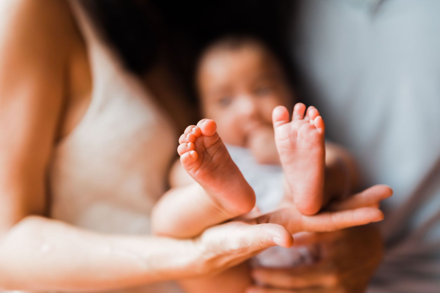 Close-up shot of tiny baby feet being gently held in adult hands.