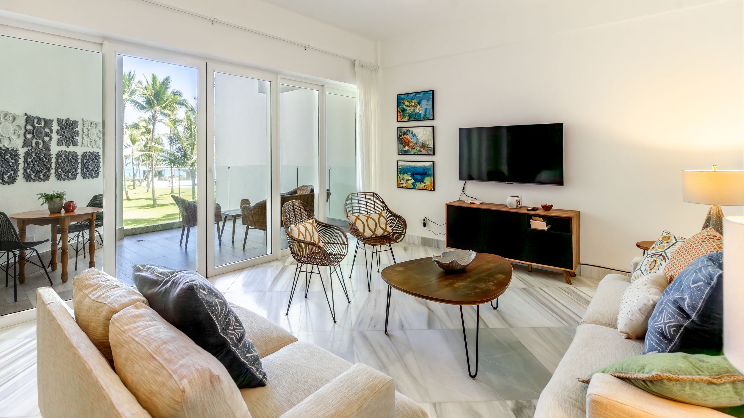 Bright beach house living room with white walls, comfortable seating and sliding glass doors.