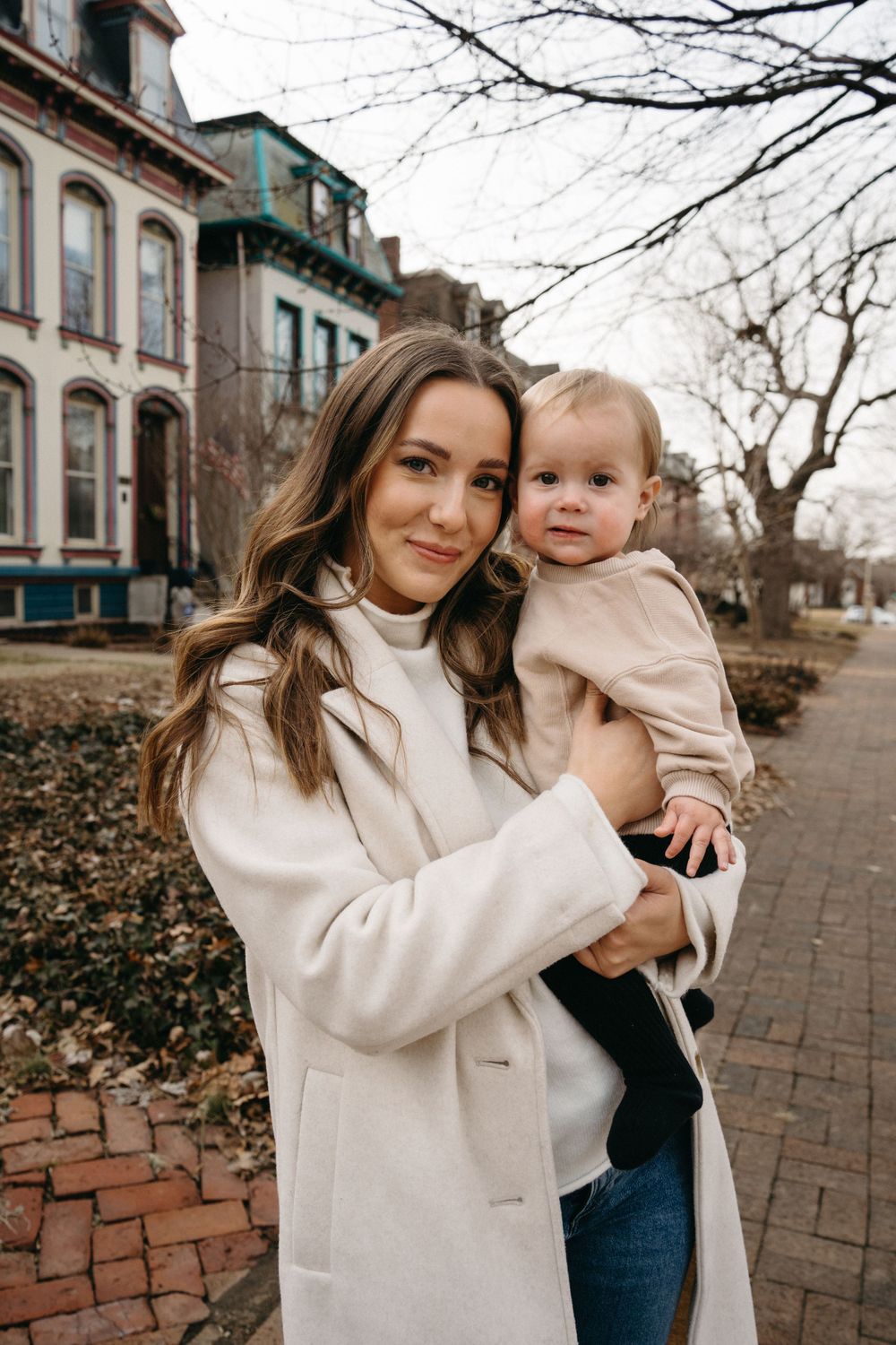 Mom and baby girl together in front of charming Victorian houses in Lafayette Square, with the historic architecture