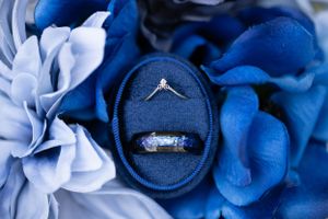 Diamond engagement ring nestled in a navy blue ring box surrounded by blue and white flowers.