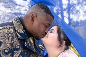Romantic wedding moment captured under blue sky in autumn setting.
