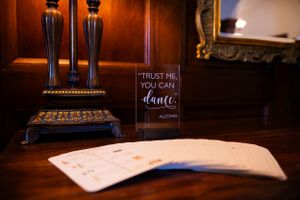 Elegant wedding detail with candlesticks and a sign that reads 'Trust me you can dance' on dark wood.