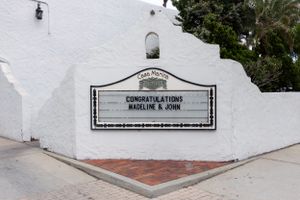 A white stucco wall with a message board and lamp fixture displaying congratulatory text.