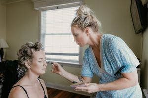 Professional makeup artist applying cosmetics during bridal preparation session.