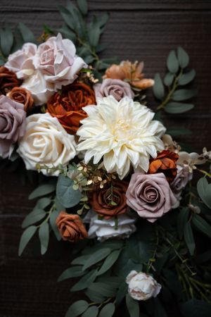 An elegant floral arrangement with roses, dahlias and eucalyptus in muted pink and burgundy tones.