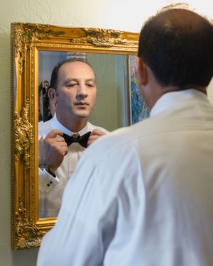 Ornate gold mirror frame reflects formal attire adjustments.