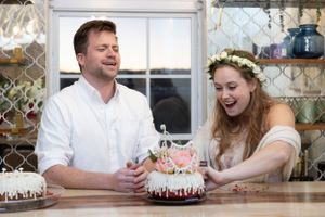 A couple shares a laugh while cutting into a decorative wedding cake.