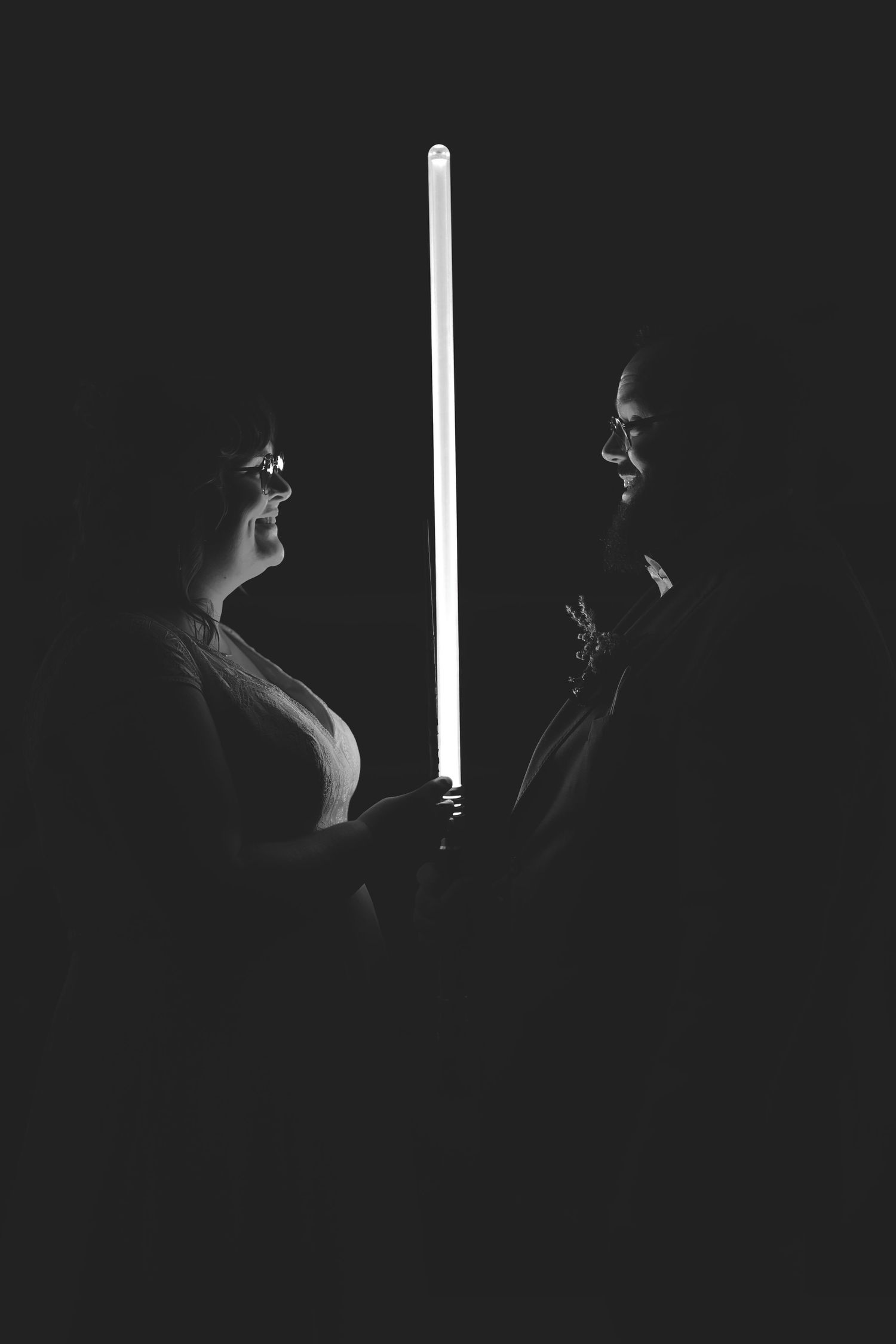 Artistic black and white portrait with glowing light beam between two silhouetted figures.