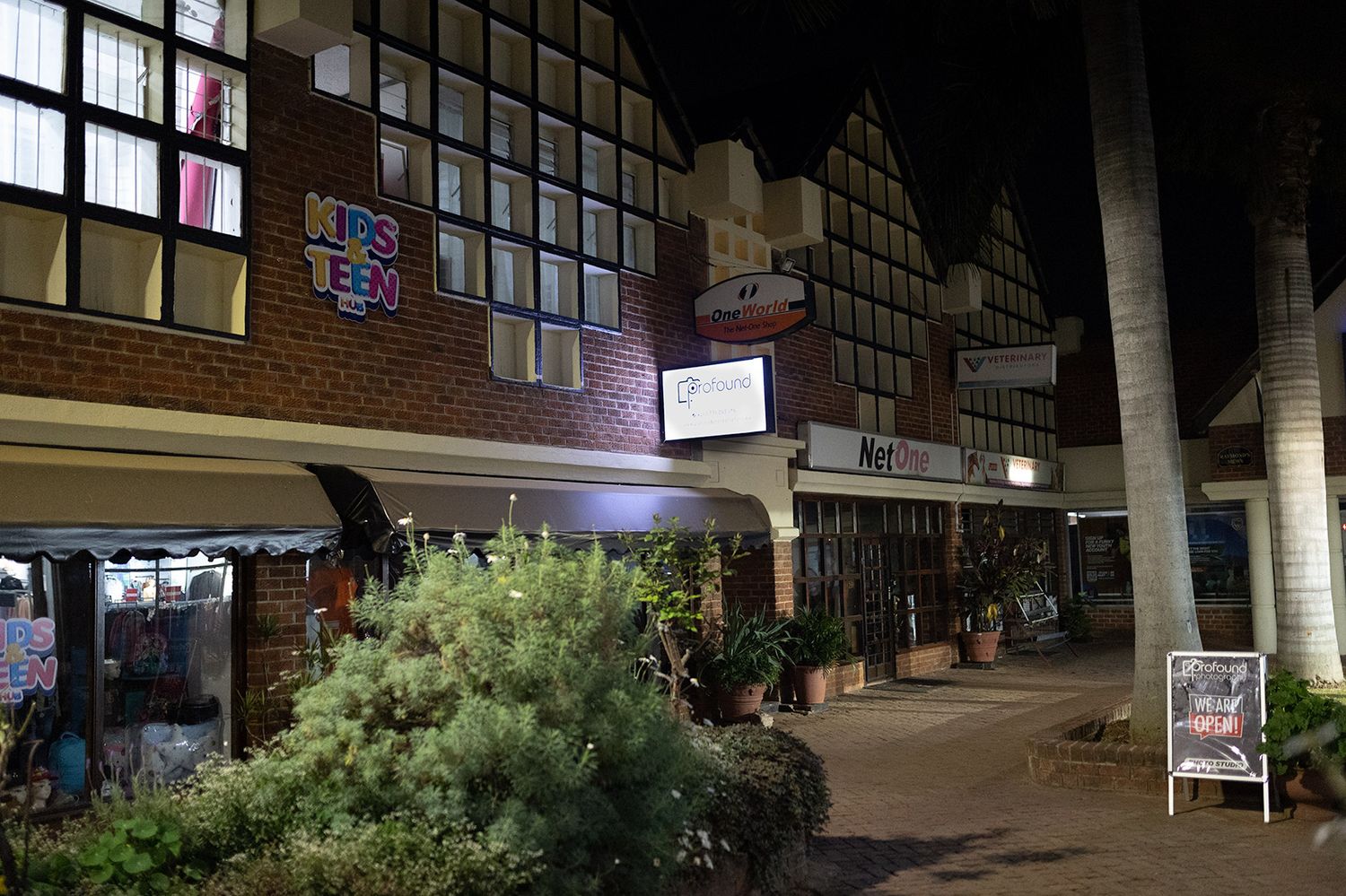 Night view of a Tudor-style shopping center with illuminated windows and storefront.
