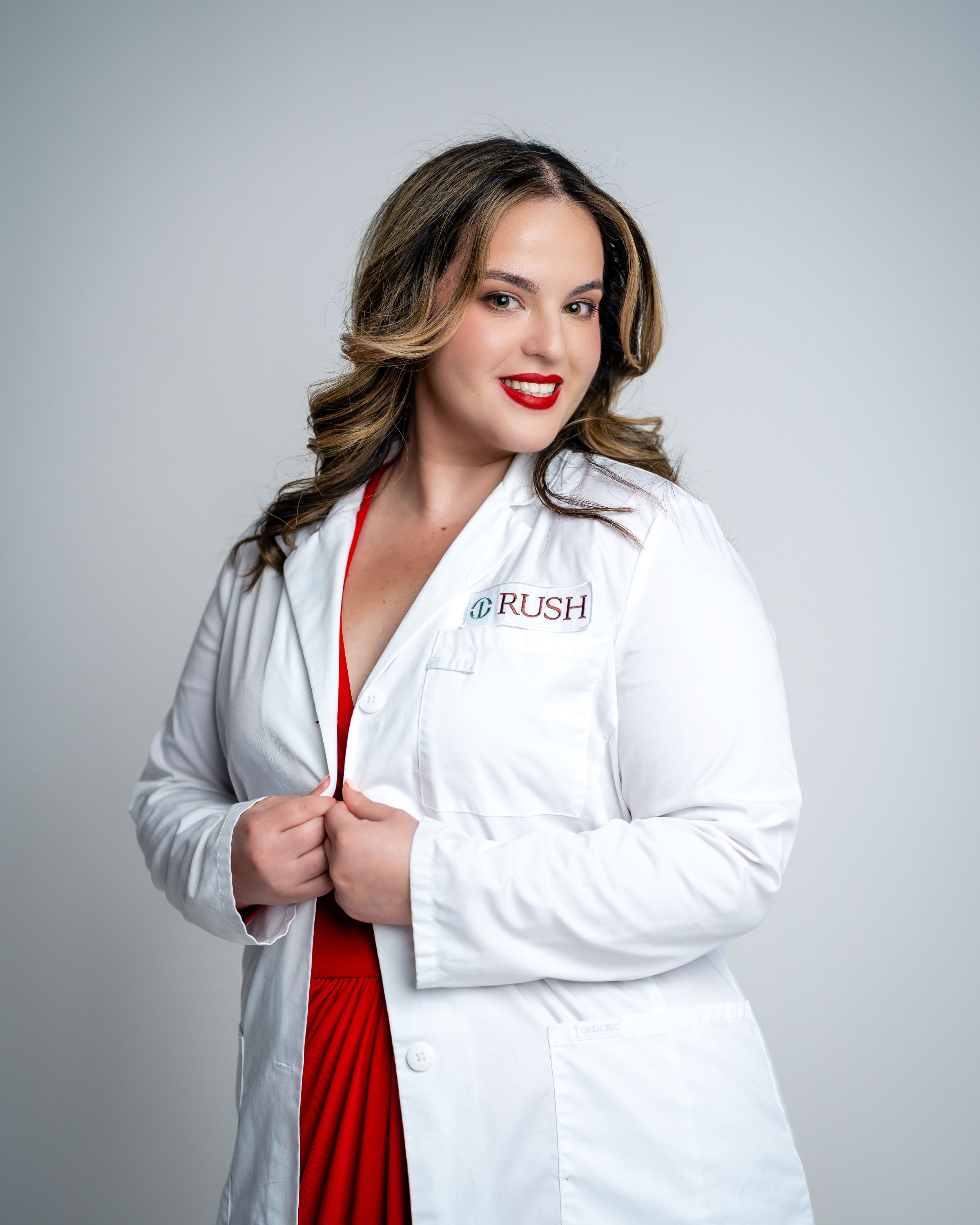 Professional portrait session in a white medical coat against a light gray studio background.