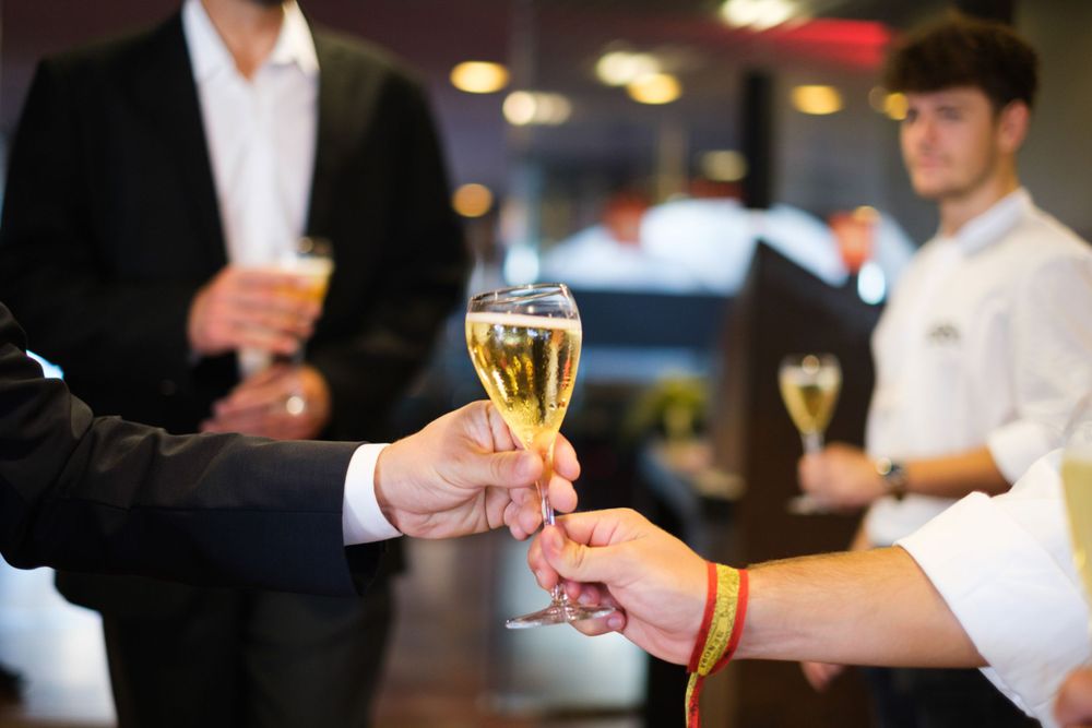 Close-up of hands toasting champagne glasses at formal business gathering.