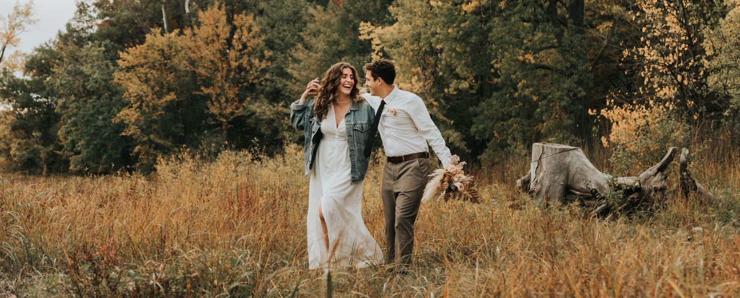 Couple walking together in golden field during autumn sunset.