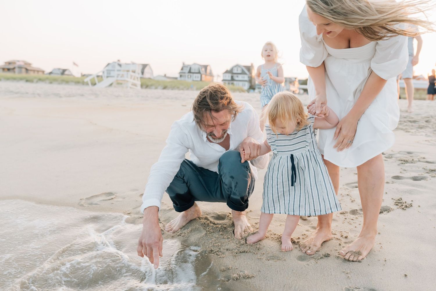 Children run to the water and splash their feet while Lauren Marie Photography captures joy in their family.