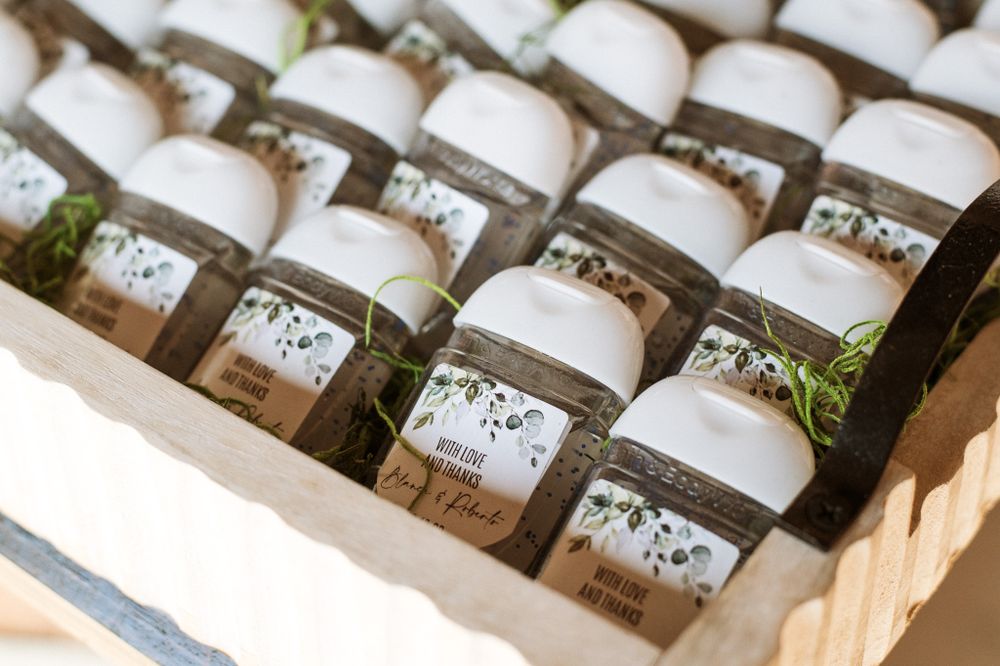 Rows of personalized wedding favor jars neatly arranged in wooden box.