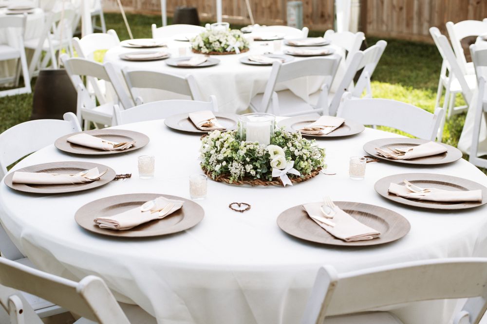 Round table settings with white linens and floral centerpieces for an elegant outdoor reception.