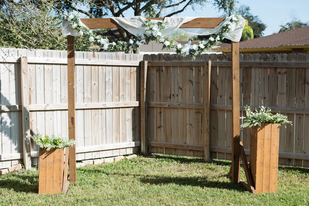 Wooden posts with flowing fabric creating an outdoor wedding ceremony arch.