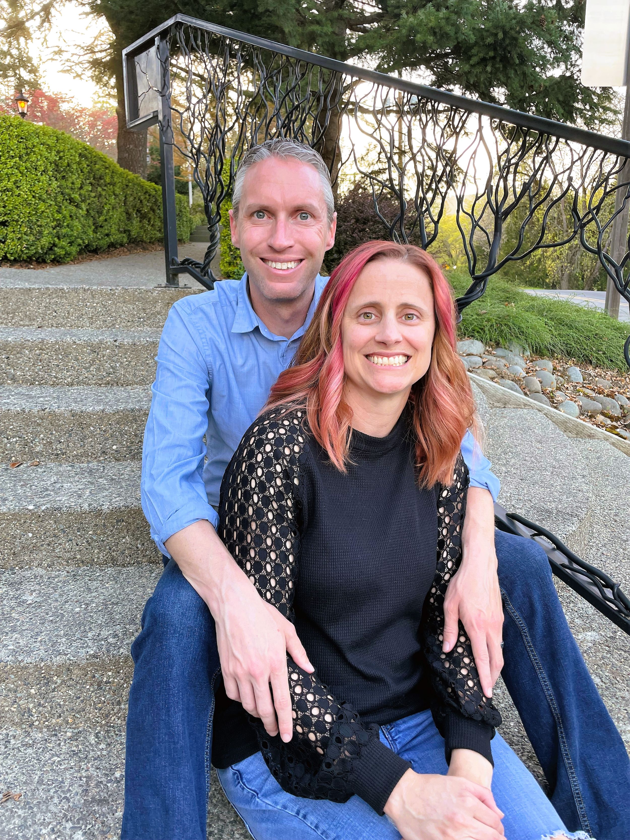 Outdoor couple photos on stone steps with greenery and brick architecture in background.