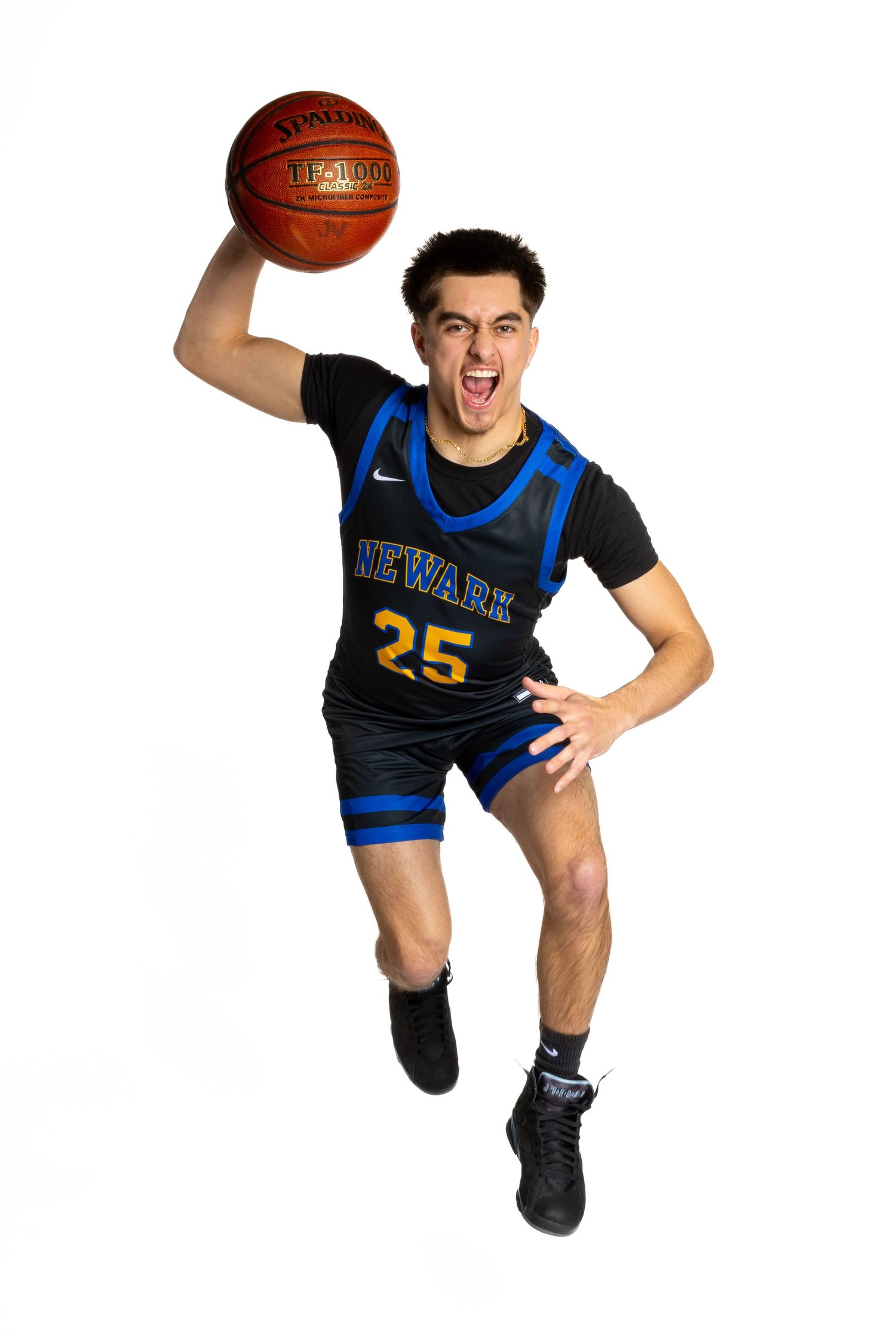 Basketball player in black and blue uniform number 25 jumping with ball against white background.