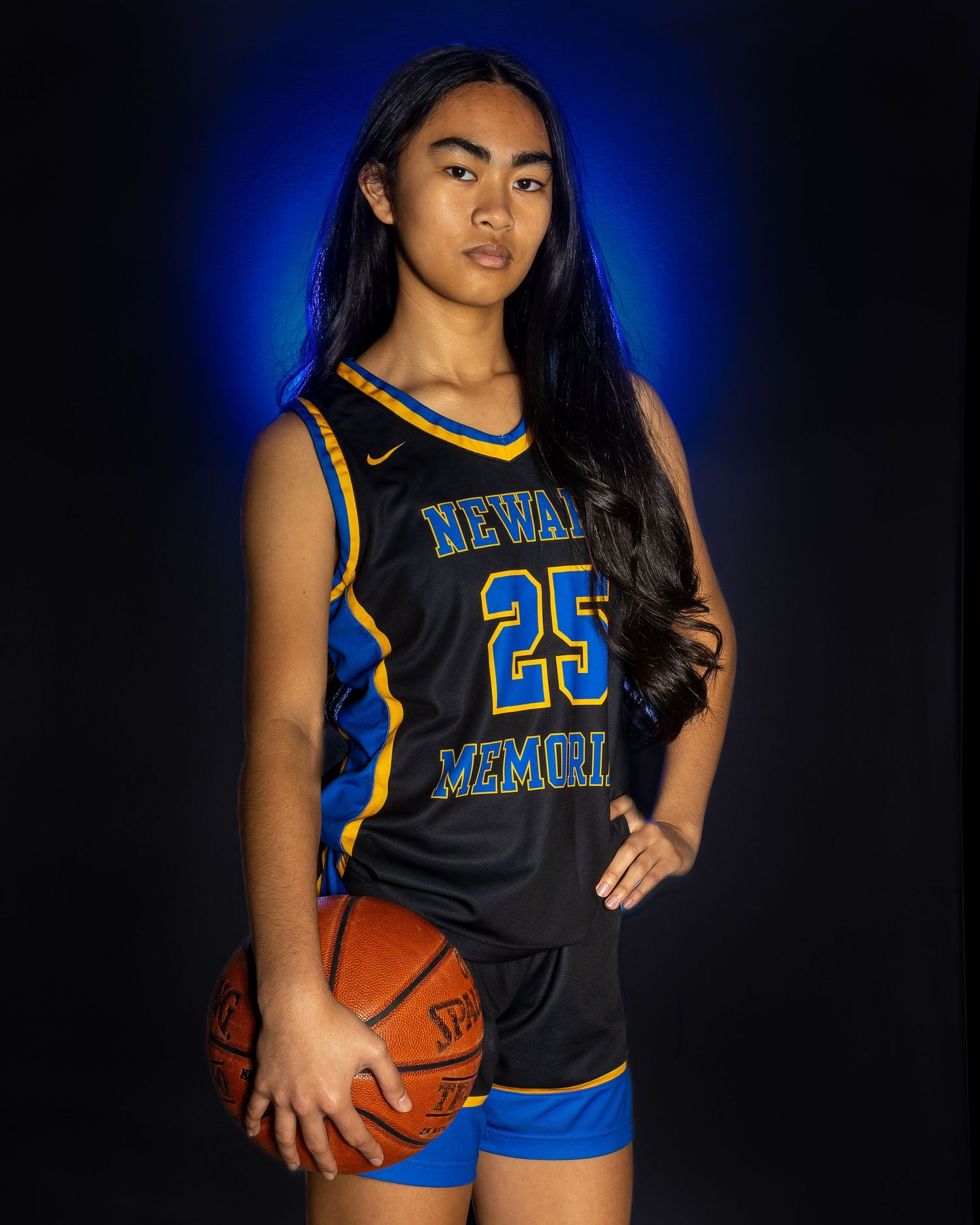 High school athlete poses with basketball in black and blue Newark basketball uniform.