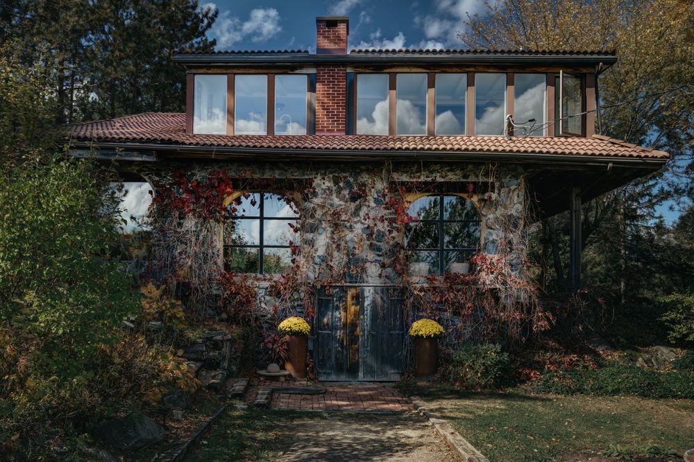 Exterior panoramic view of a modern building with large windows surrounded by autumn trees.