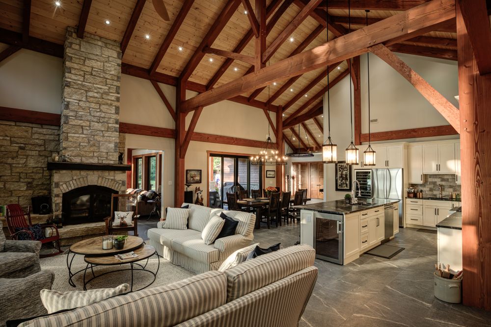 Spacious living area with timber frame ceiling, stone fireplace, and comfortable seating.