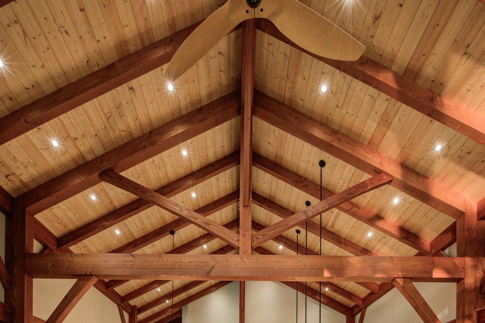 Vaulted wooden ceiling with exposed timber frame trusses and integrated lighting.