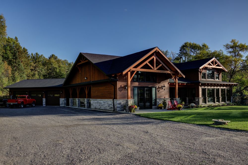 Wide angle exterior view of a timber frame lodge with stone accents and gravel parking area.