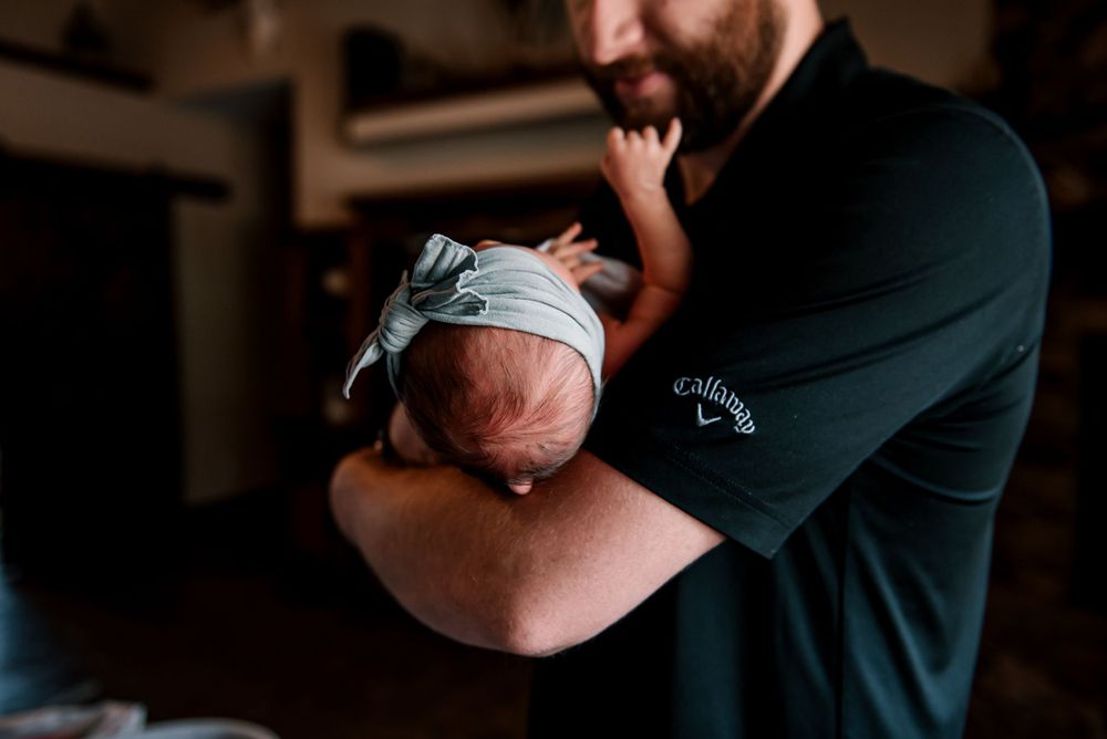 Close-up of tender moment between parent and infant in low light setting.