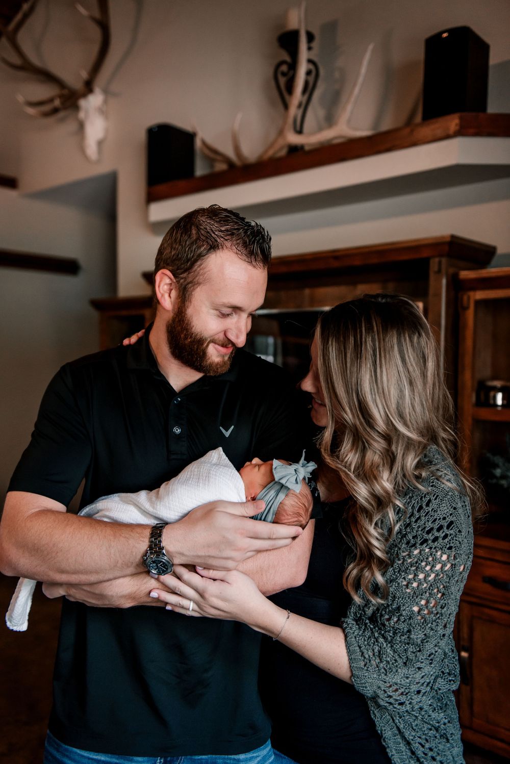Family embracing while holding their newborn in cozy home setting.