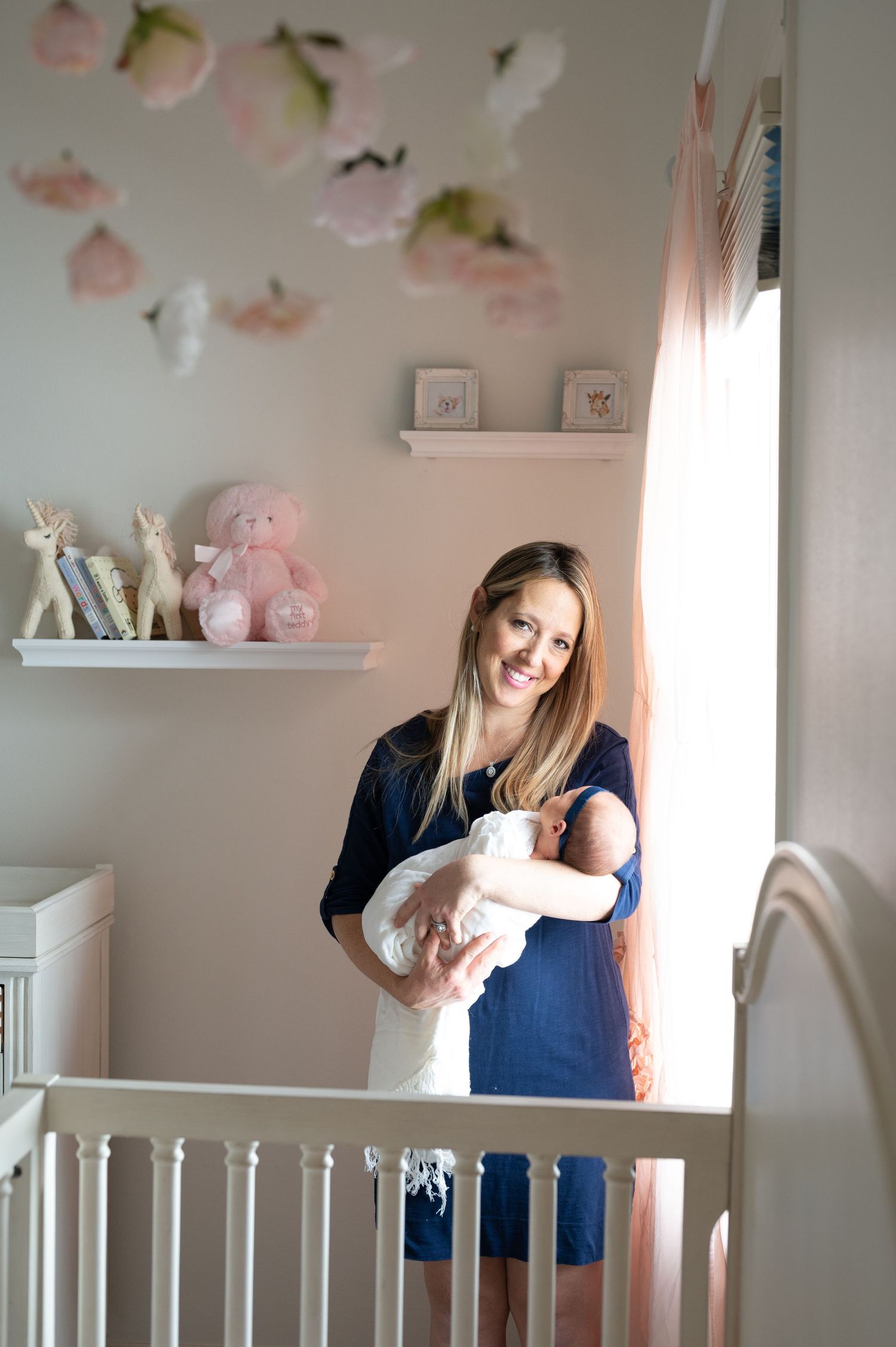 cascading pink flowers inside the nursery the mother smiles at the camera during a lifestyle session in houston
