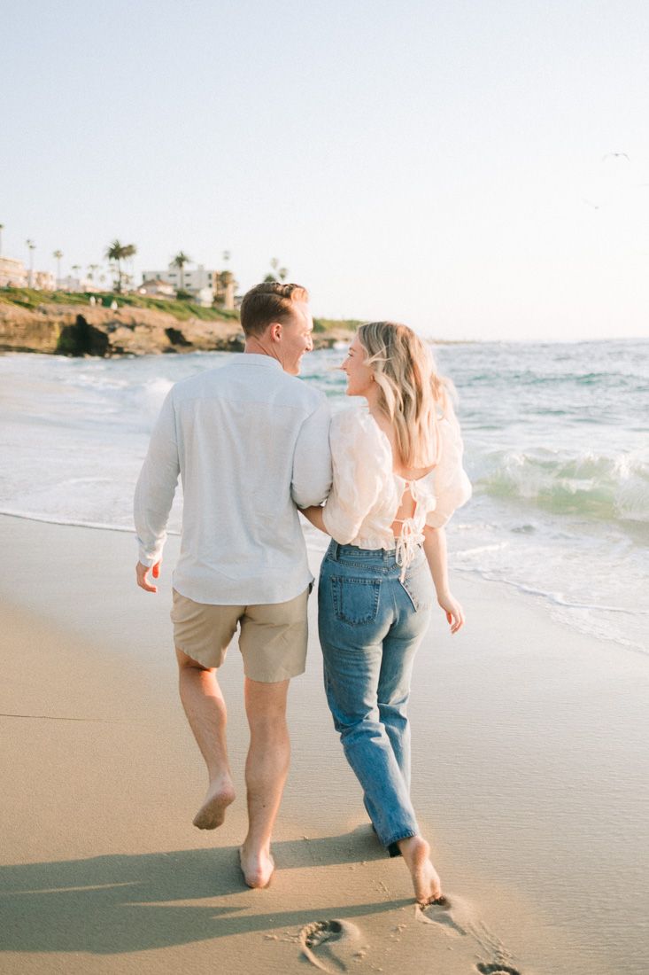 A couple takes a romantic stroll along the shoreline during sunset at the beach.