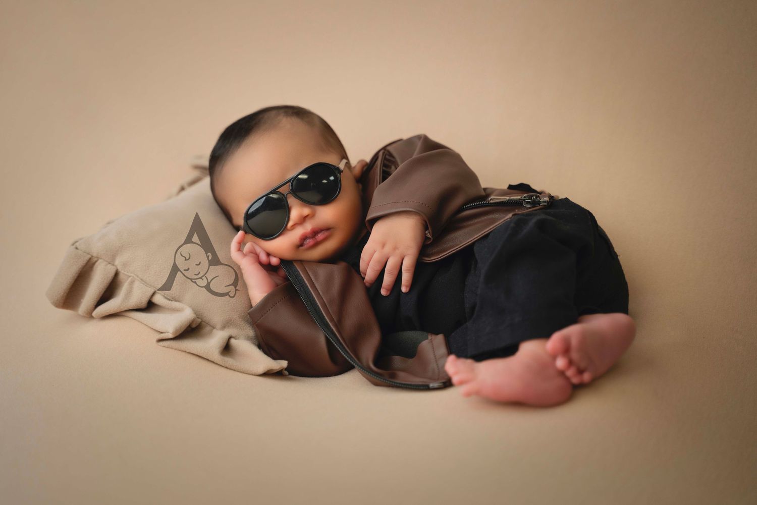 Stylishly dressed baby wearing sunglasses and casual attire during a professional photo shoot.