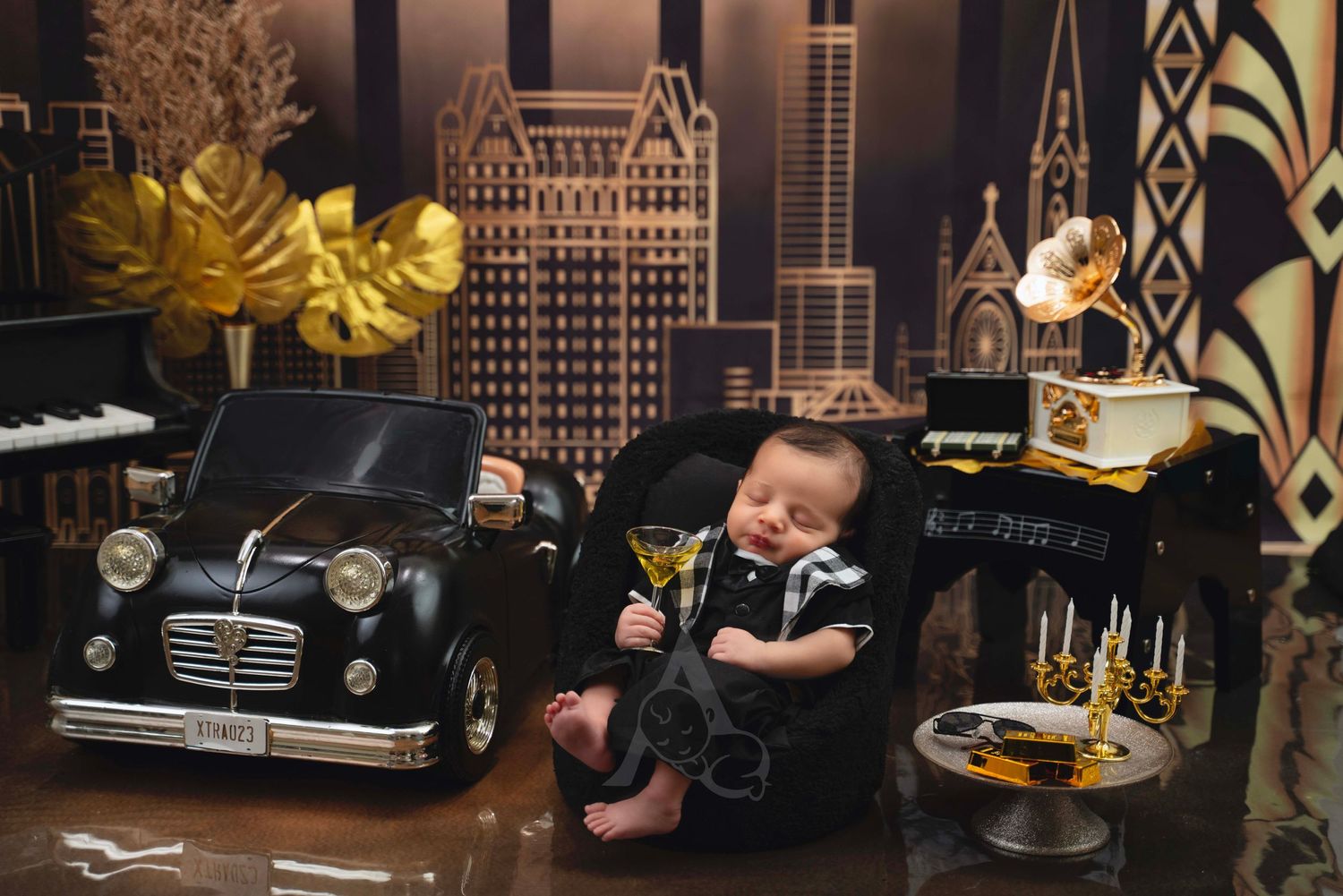 Vintage-themed newborn photo with classic car props and art deco city backdrop.